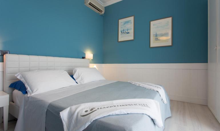 Camera moderna con pareti blu e letto matrimoniale.