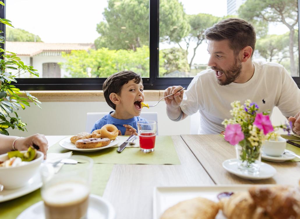 Padre e figlio sorridono felici mentre fanno colazione insieme.